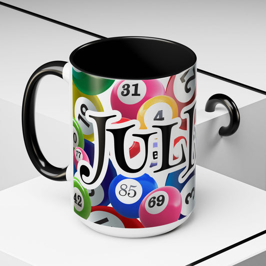 A ceramic mug with a black handle and interior, featuring a colorful print of bingo balls and the custom name 'JULISSA' in large black letters. The mug is shown on a clean, light gray geometric background.