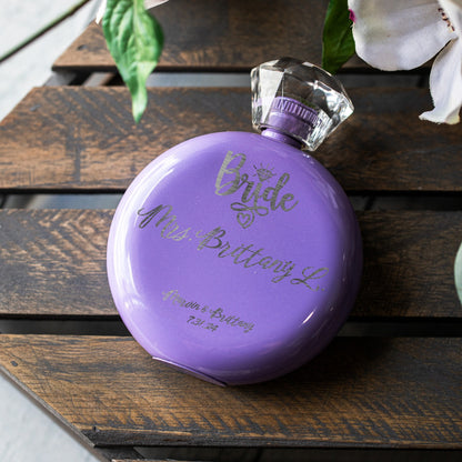 A round purple flask with a clear faceted cap, personalized with laser etched text reading 'Bride Mrs. Brittany L.