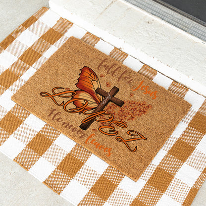 A rectangular cork doormat with a fall-themed graphic featuring a butterfly, cross, and the words 'Fall For Jesus' and 'He Never Leaves'  with the custom name 'Lopez' and its placed on a white and tan checkered blanket.