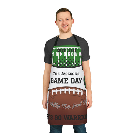 A man modeling a custom sports apron with a football theme, featuring a green field pattern at the top, 'THE JACKSONS GAME DAY' text in the middle, and a brown football graphic at the bottom.