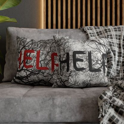 A gray throw pillow with a black tree branch pattern and the word 'HELP' in red and black letters, styled on a gray sofa with a plaid blanket in a modern living room setting.