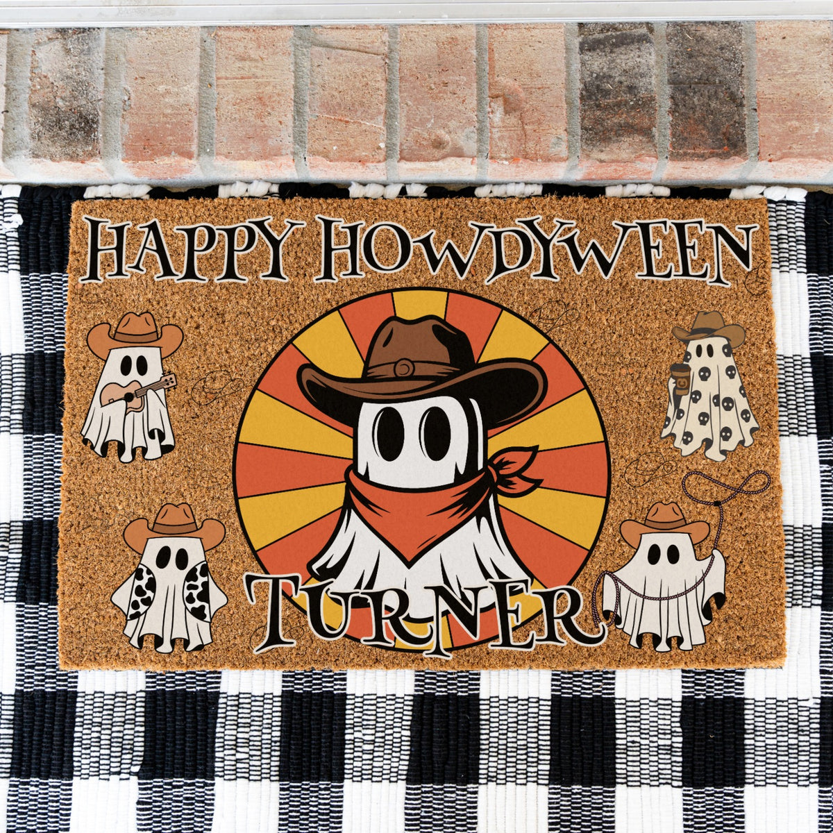 A rectangular doormat with a Halloween western theme, featuring the text 'HAPPY HOWDYWEEN TURNER' and a central ghost wearing a cowboy hat and bandana, surrounded by four smaller ghost illustrations. The doormat is placed on a black and white checkered rug in front of a brick floor.