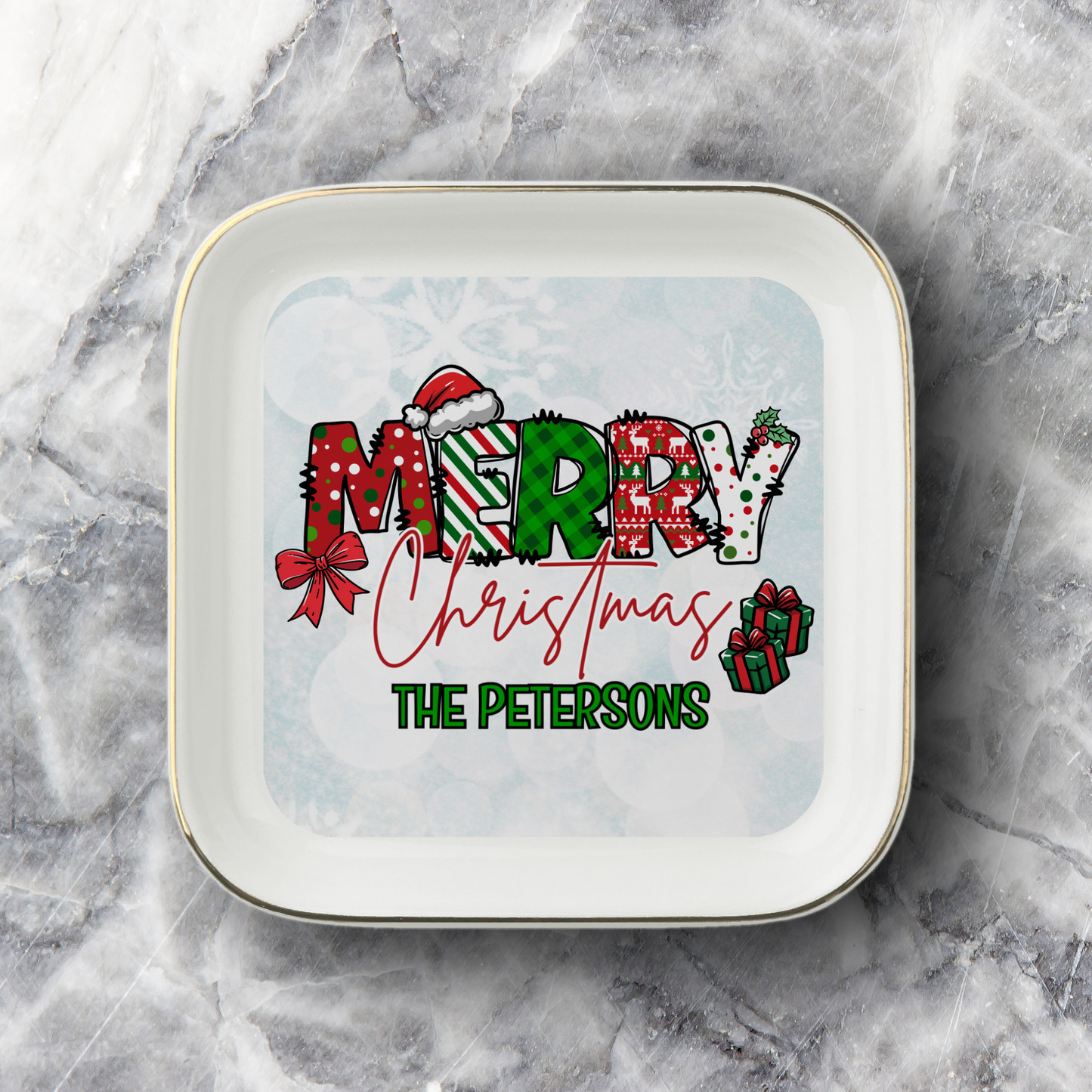 A square white ceramic plate with rounded corners and a thin gold rim, featuring a personalized Christmas design. The design displays the word 'MERRY' in festive patterned letters, a red bow, the phrase 'Christmas' in red cursive, and the name 'THE PETERSONS' in green block letters, all set against a snowflake pattern.