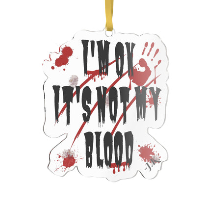A die-cut acrylic hanging ornament with a white background and a yellow hanging loop. The ornament features the text 'I'M OK IT'S NOT MY BLOOD' in a dripping black font, decorated with red blood splatters, a red handprint, and diagonal red scratch marks.