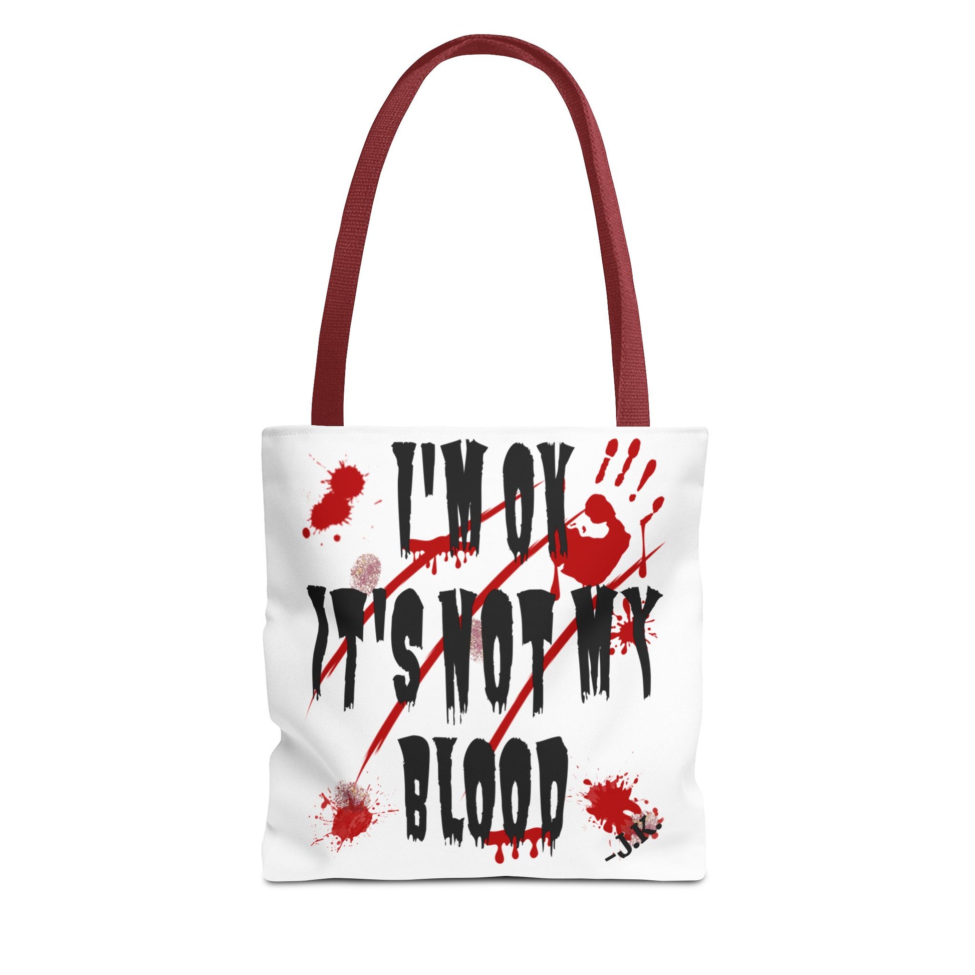 A white canvas tote bag with red shoulder straps, featuring a graphic print of the text 'I'M OK IT'S NOT MY BLOOD' in black with red blood splatters and a handprint design.