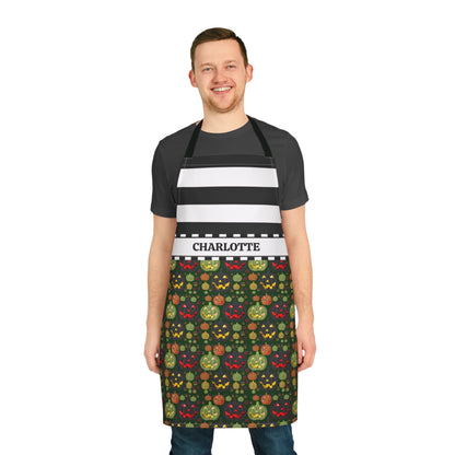 A man wearing a black and white striped apron with a personalized name band reading 'CHARLOTTE' and a dark green Halloween-themed patterned lower section, standing against a plain white background.