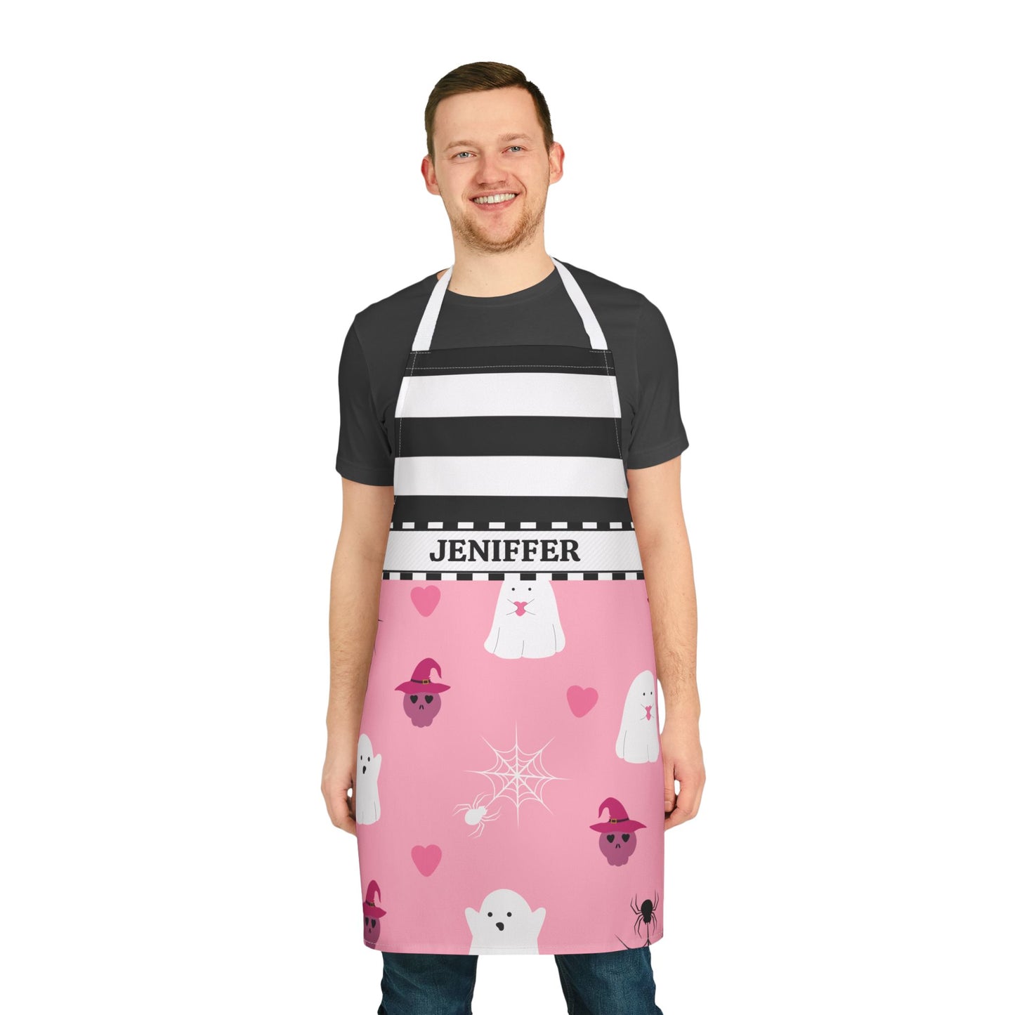 A man wearing a bottom pink Halloween-themed apron with white ghosts, pink ghosts, and a black-and-white striped upper section over a black t-shirt, shown against a plain white background.