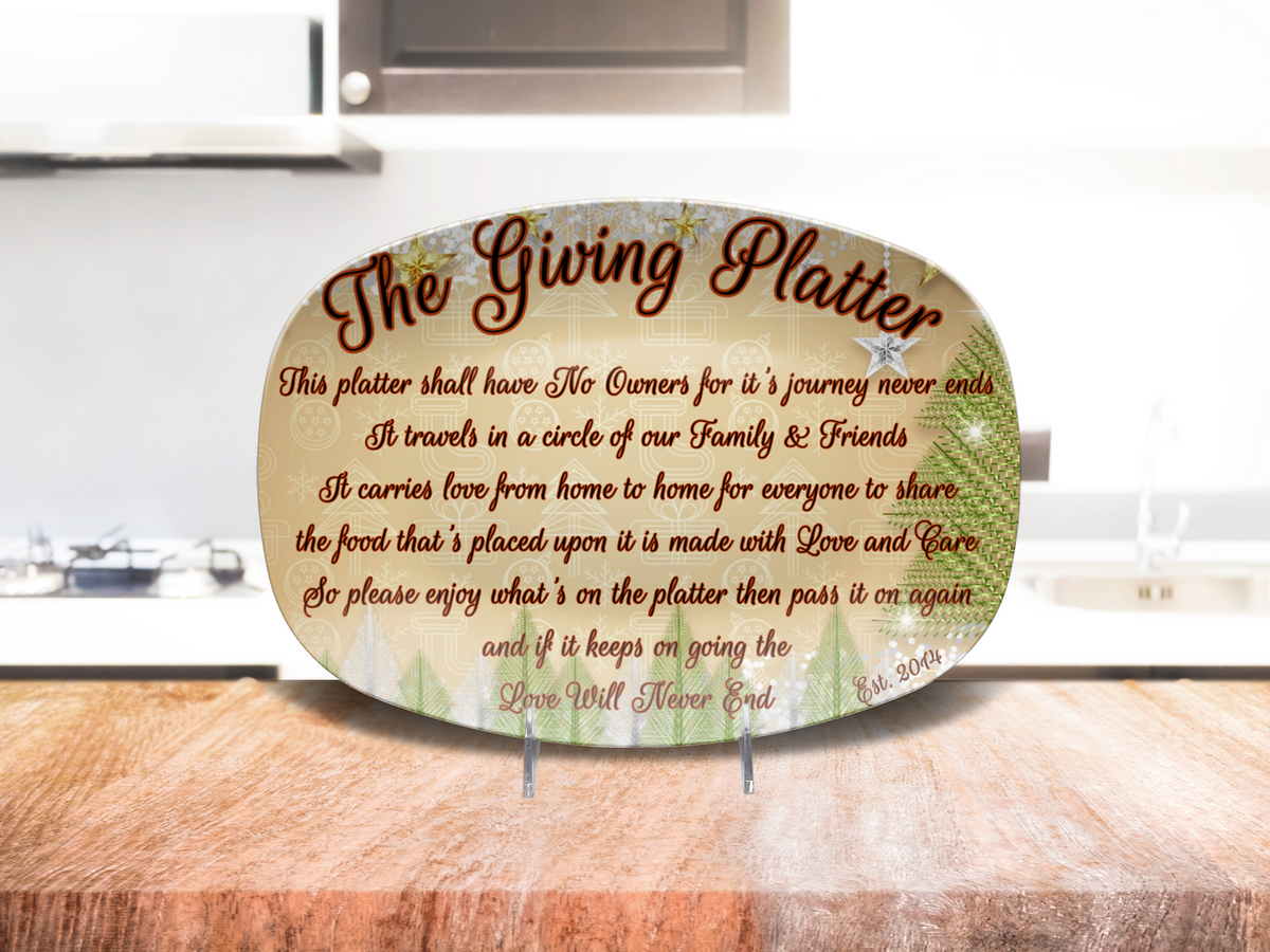 An oval decorative platter reading 'The Giving Platter' with printed script and est year, displayed on a wooden surface in front of a blurred kitchen background.