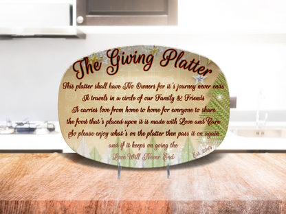 An oval decorative platter reading 'The Giving Platter' with printed script and est year, displayed on a wooden surface in front of a blurred kitchen background.