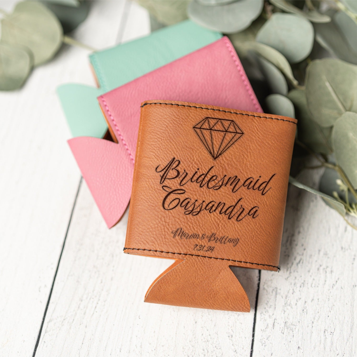 A tan leather can cooler with a diamond graphic and the custom engraved text 'Bridesmaid Cassandra' and 'Marvin & Brittany 7.31.24