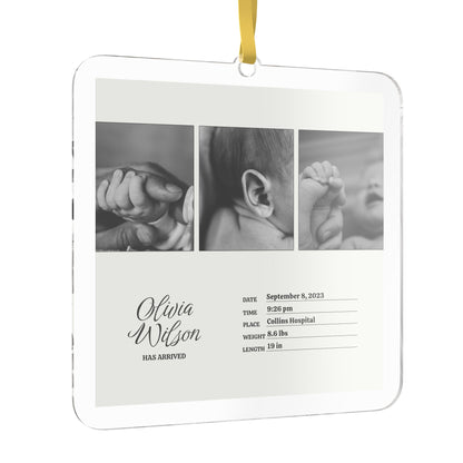A square beige baby keepsake photo ornament with rounded corners, hanging from a yellow ribbon. The front features three custom black-and-white newborn photos, personalized text reading 'Olivia Wilson HAS ARRIVED,' and baby details printed in black on a clean white background.