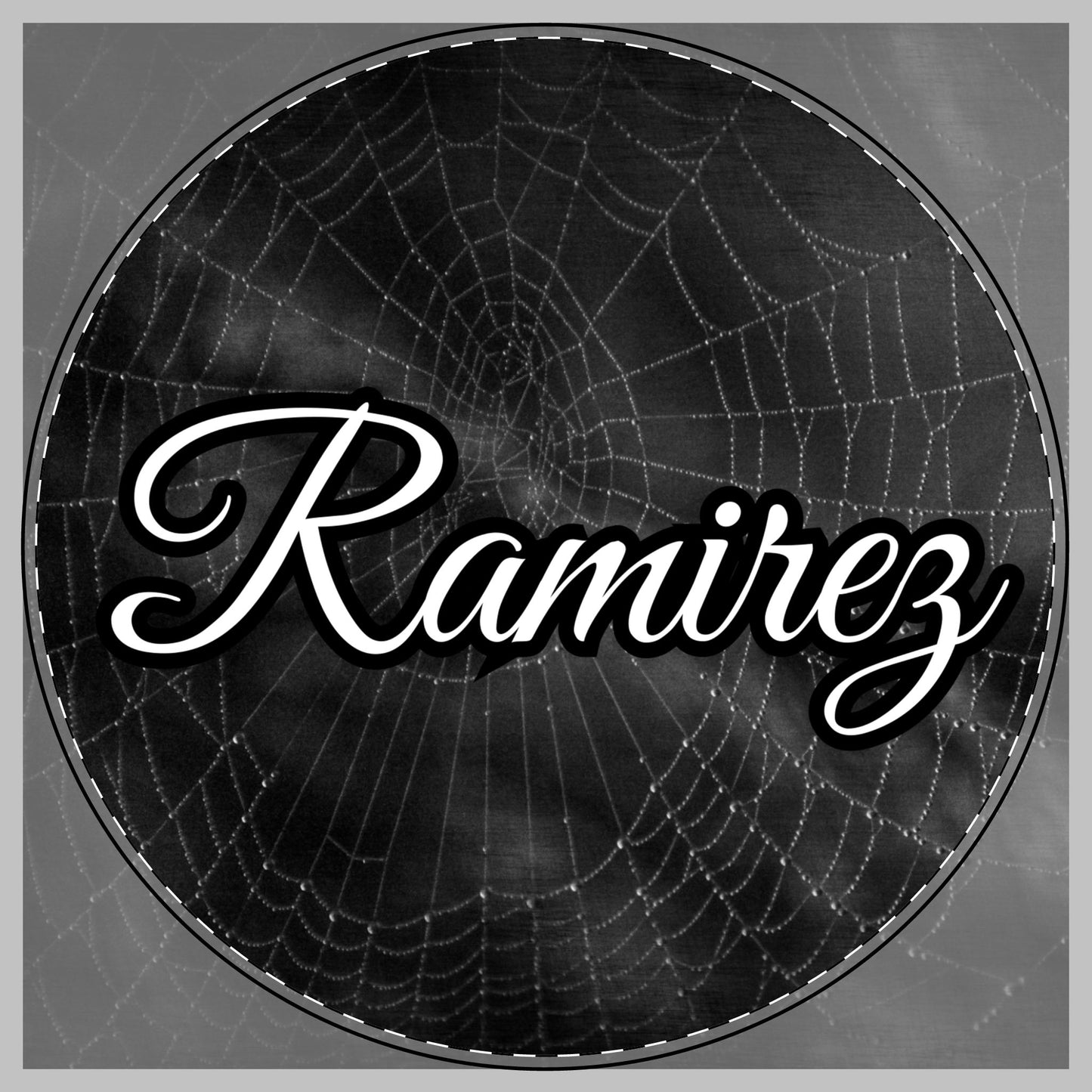 A circular black and white graphic featuring a spiderweb pattern with the name 'Ramirez' written across the center in large white cursive script with a black outline for a citting board.